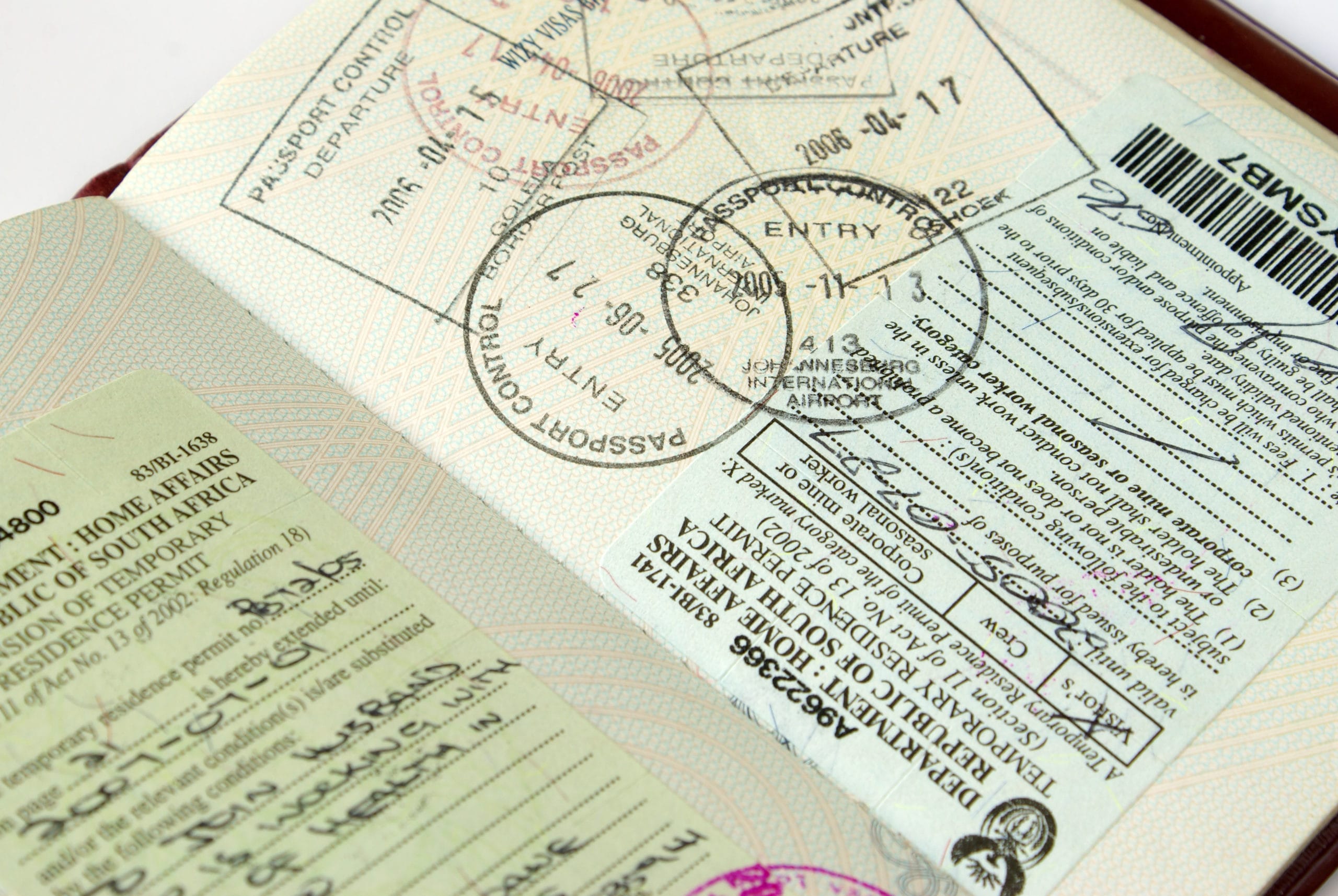 A South African temporary residence permit and various international passport entry stamps, illustrating global mobility and work visa requirements.
