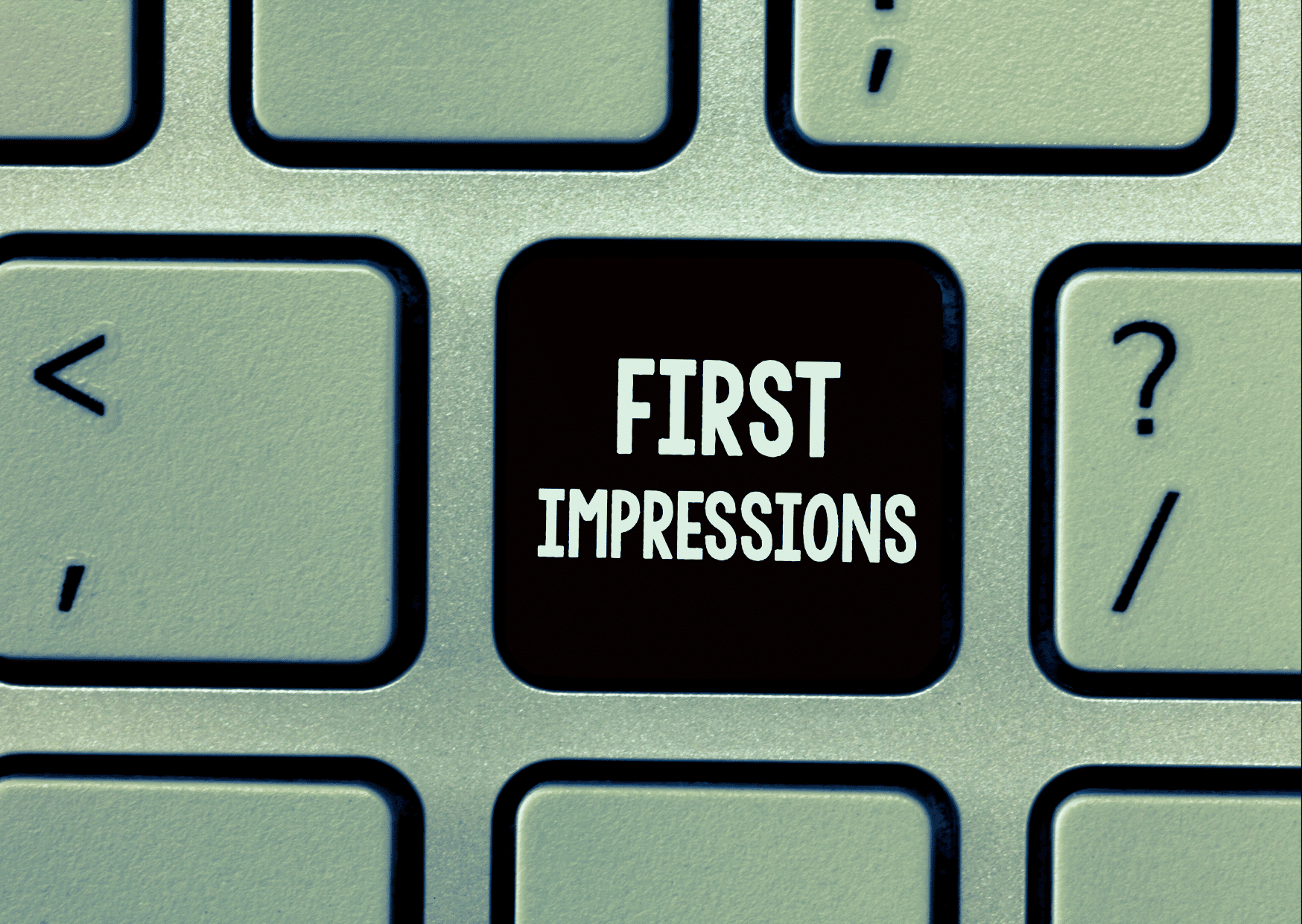 A close-up of a computer keyboard with a black custom key that reads 'FIRST IMPRESSIONS' in bold white text.
