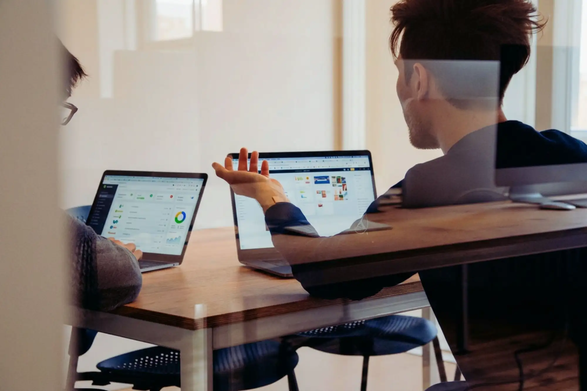 DevOps engineer talking to a colleague infront of their laptops