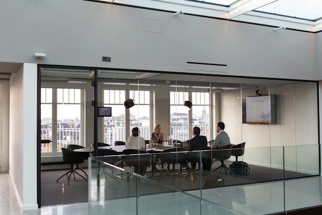 Team meeting in a glass-walled boardroom, discussing a hiring decision